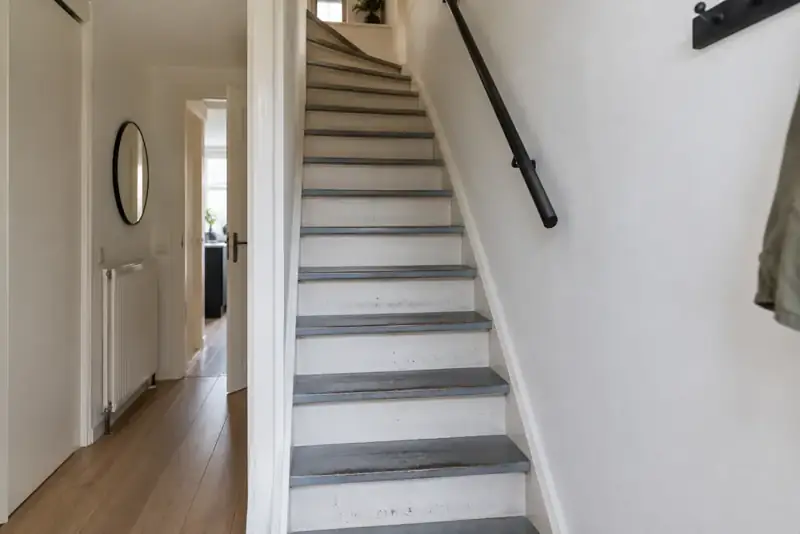 Voor renovatie: steile jaren 70 trap met beschadigde witte verf en oude grijze treden