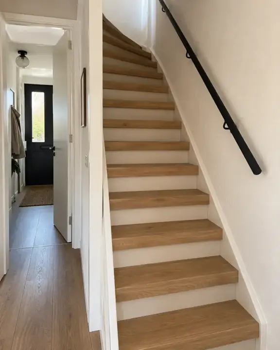 Rechte besloten trap in een jaren 80 woning met honingkleurige eikenlook laminaattreden